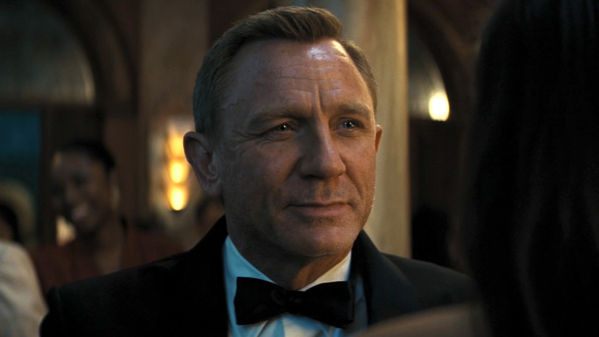 Daniel Craig smiling in a tux at Ana de Armas in No Time to Die. 