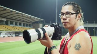 Photographer James Artaius using the Sony A9 III with Sony 300mm lens, standing in a floodlit track and field stadium at night