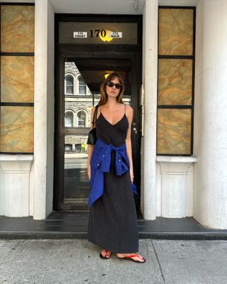 Woman in black slip dress and red thong sandals.