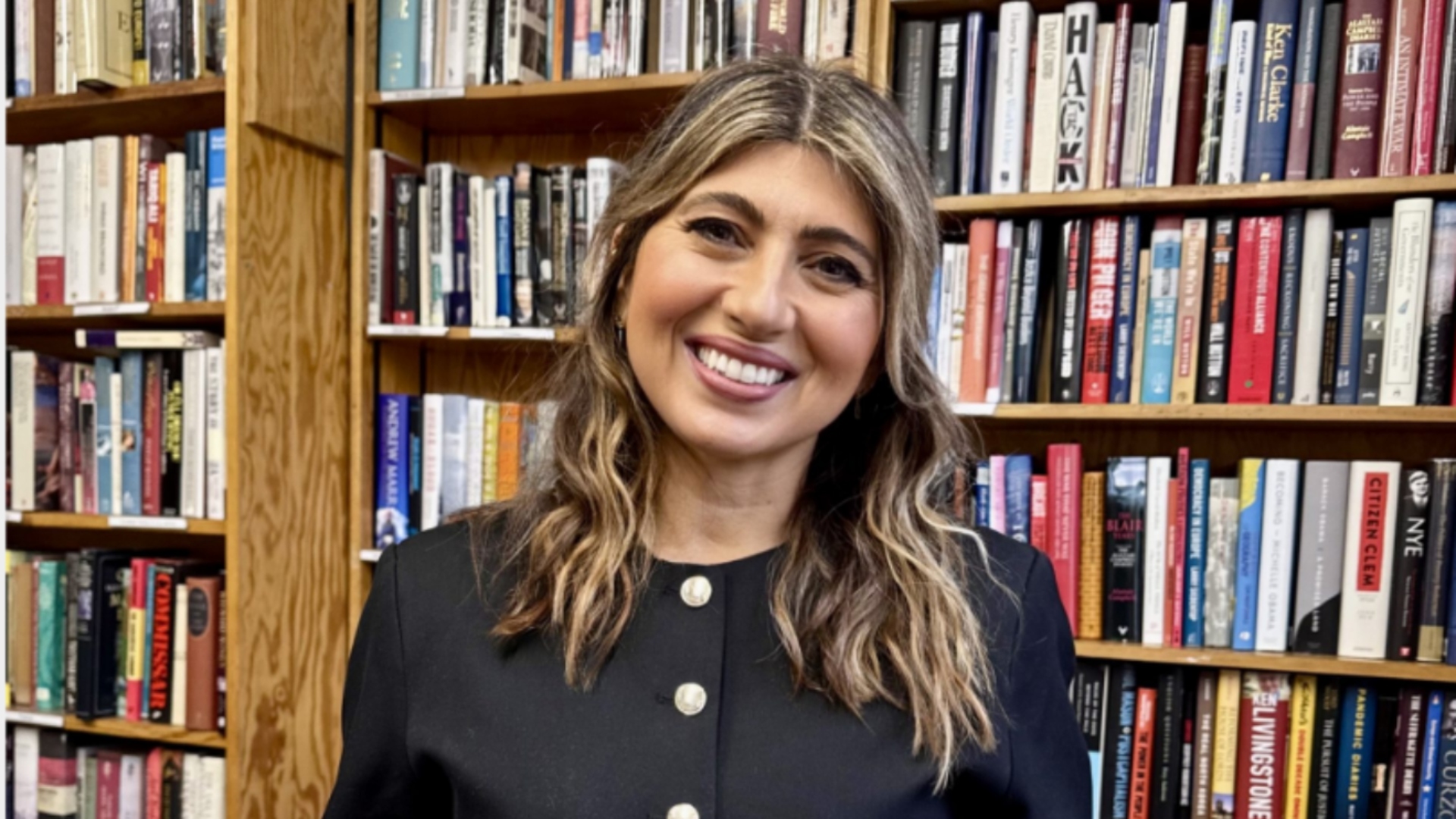 Olga Thompson next to a bookshelf
