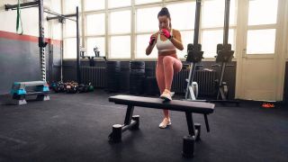 Woman performs a step-up using a weights bench