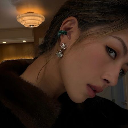 Lily Muni He wearing a fur-collar jacket with a green ear cuff and clear earrings..