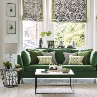 White living room with bay window, patterned blinds and green sofa