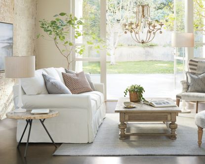 A white slipcovered sleeper sofa in a light and airy living room