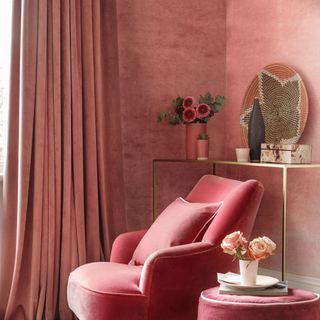 living area with pink wall and pink arm chair and side table and curtains