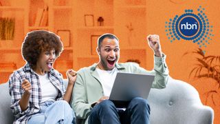 Young couple sitting on a sofa with a laptop and looking excited.