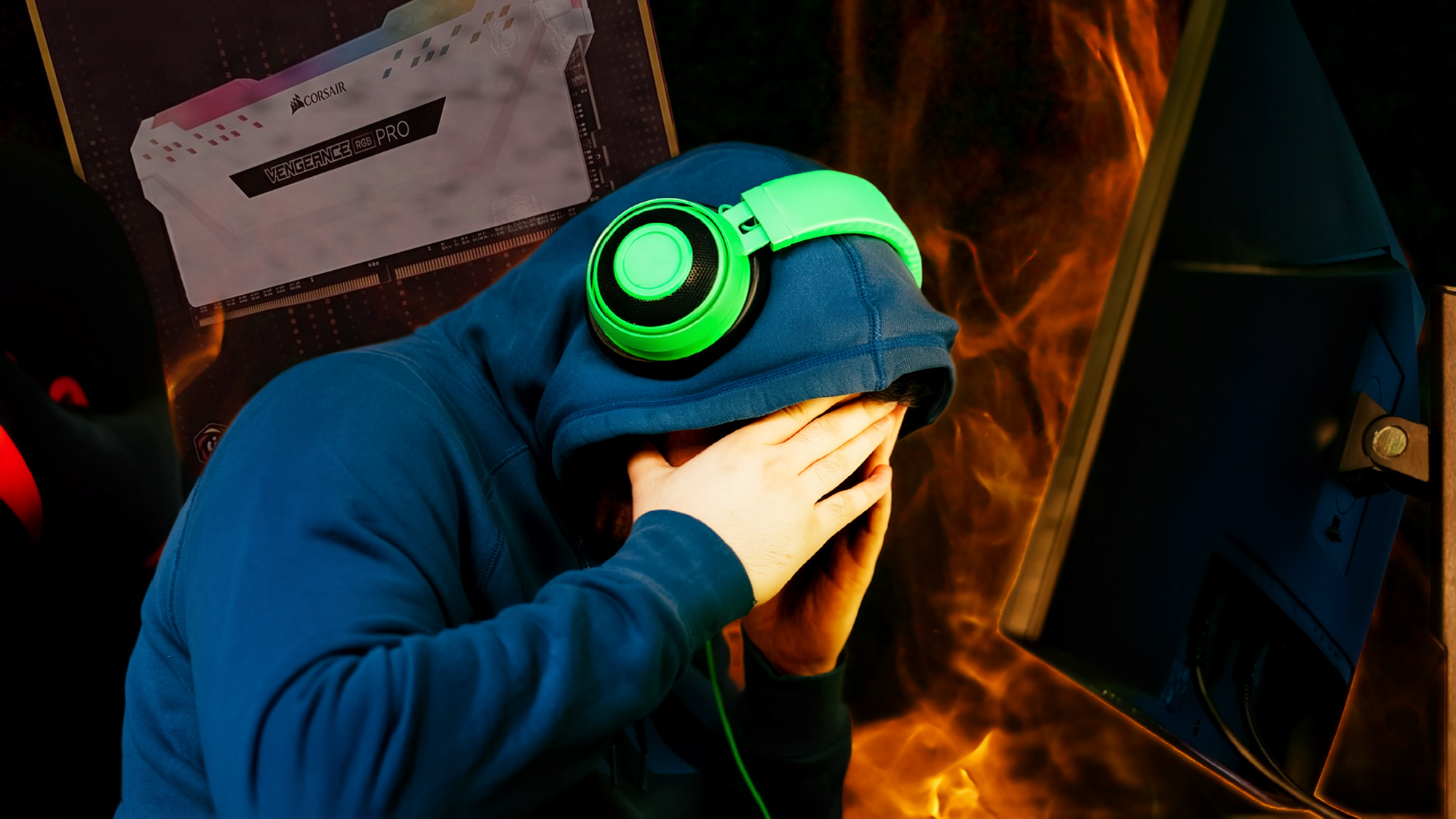 A person in a blue hoodie and bright green headphones sits at a computer desk with their face buried in their hands. A RAM box is visible behind them, and stylized flames fill the background