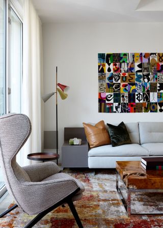 A mid century modern style living room with wingback chair, white leather sofa and retro wall art