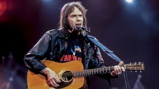 Canadian Folk and Rock musician Neil Young plays guitar as he performs onstage during the Farm Aid benefit concert, Indianapolis, Indiana, April 7, 1990. 