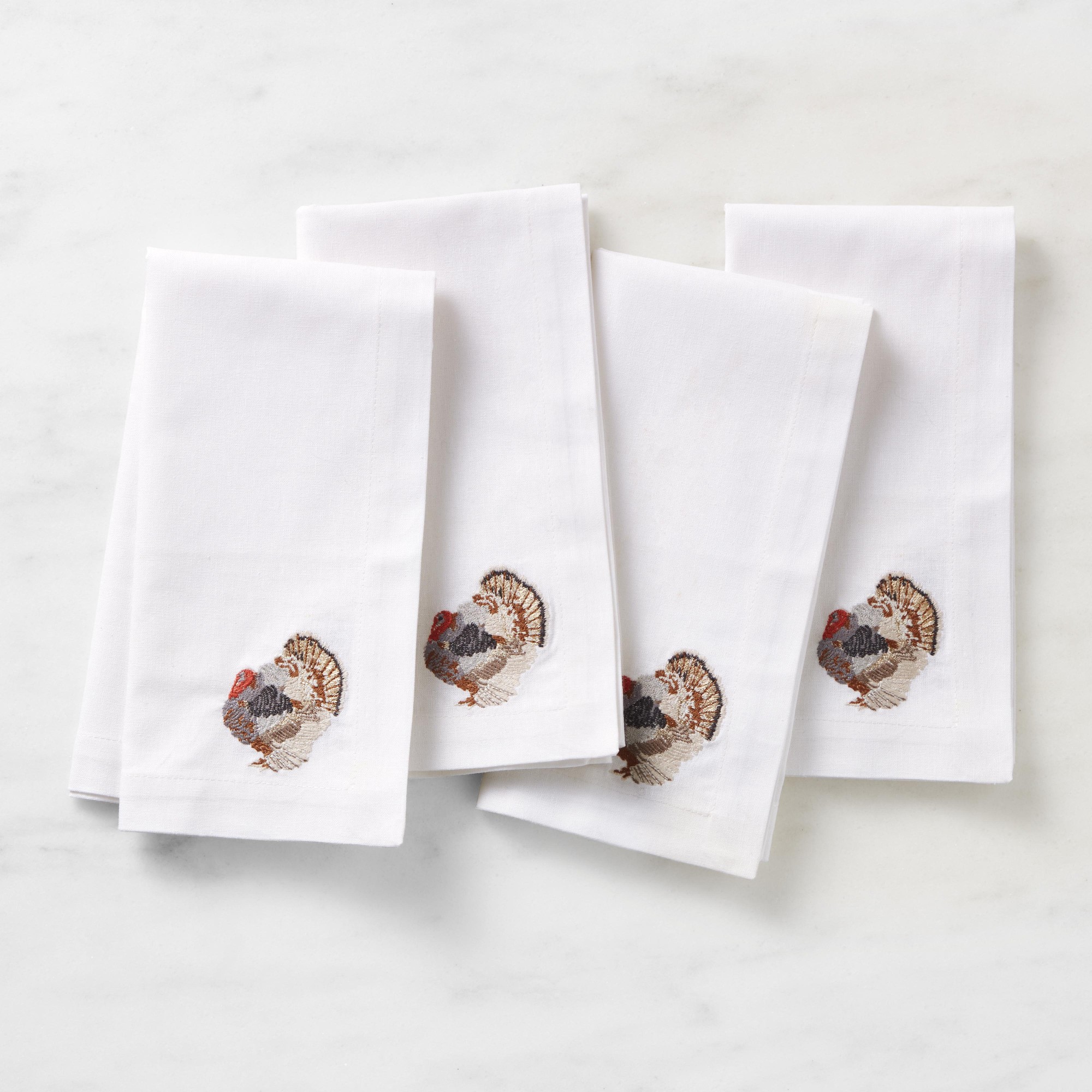 Four white napkins embroidered with turkeys