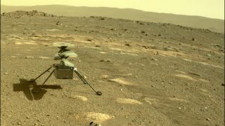 a small helicopter sits in red rocky dirt