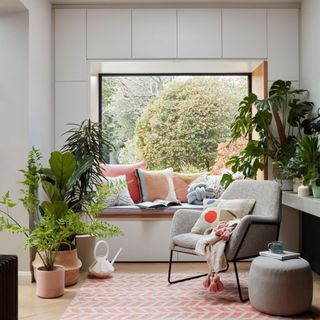 living room with white wall glass window plants and grey chair