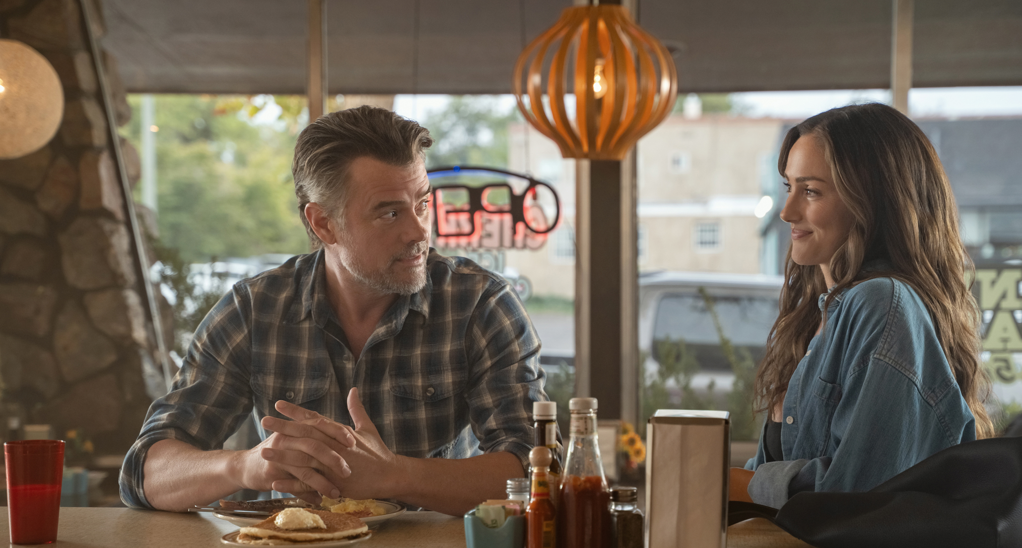 josh duhamel and minka kelly talk at a diner bar during breakfast in a still from ransom canyon season 2 
