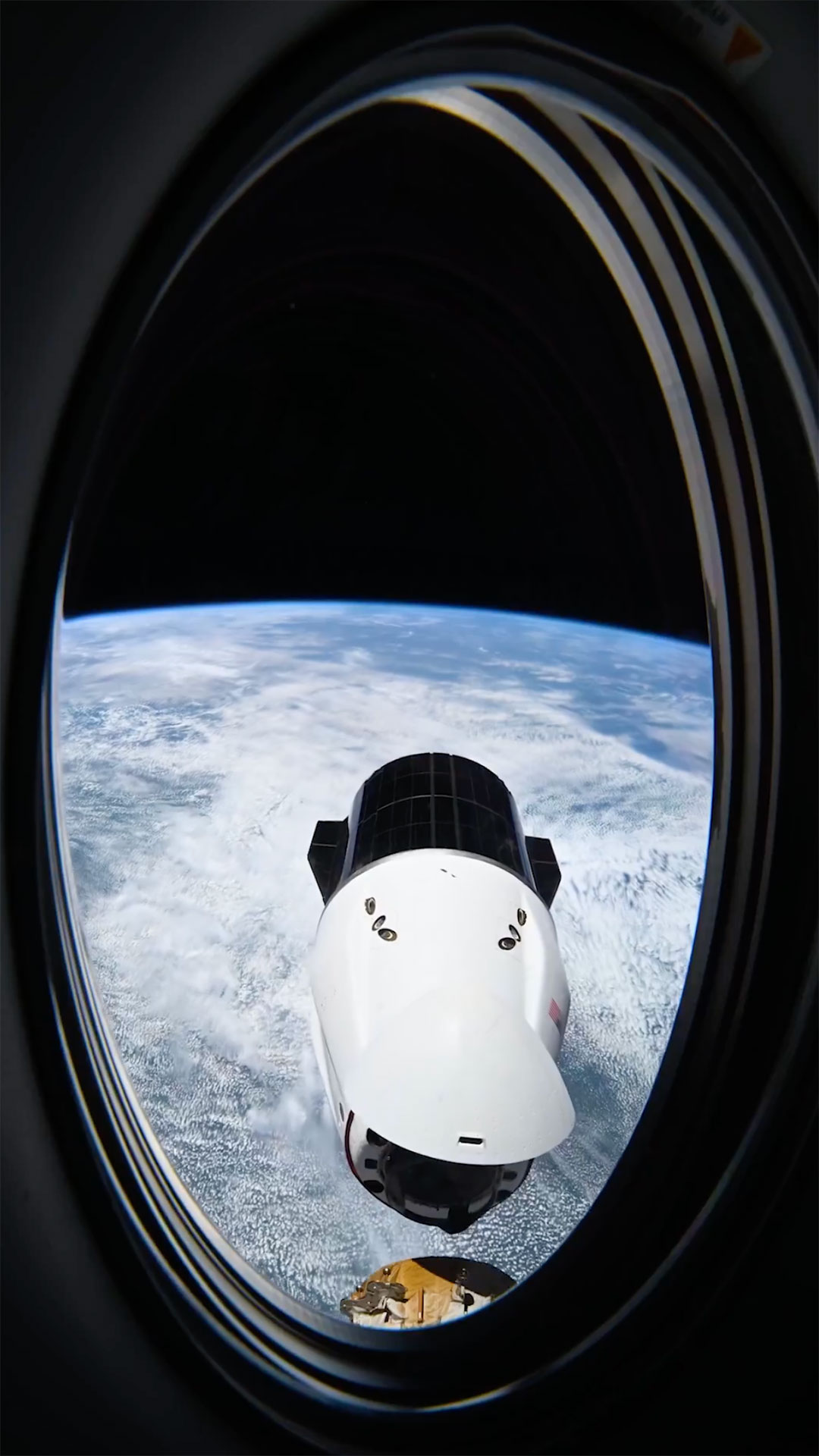 a white and black spacecraft is seen approaching a docking to a space station in Earth orbit