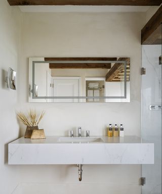A bathroom with marble floating vanity, rectangular mirror and walk-in marble shower