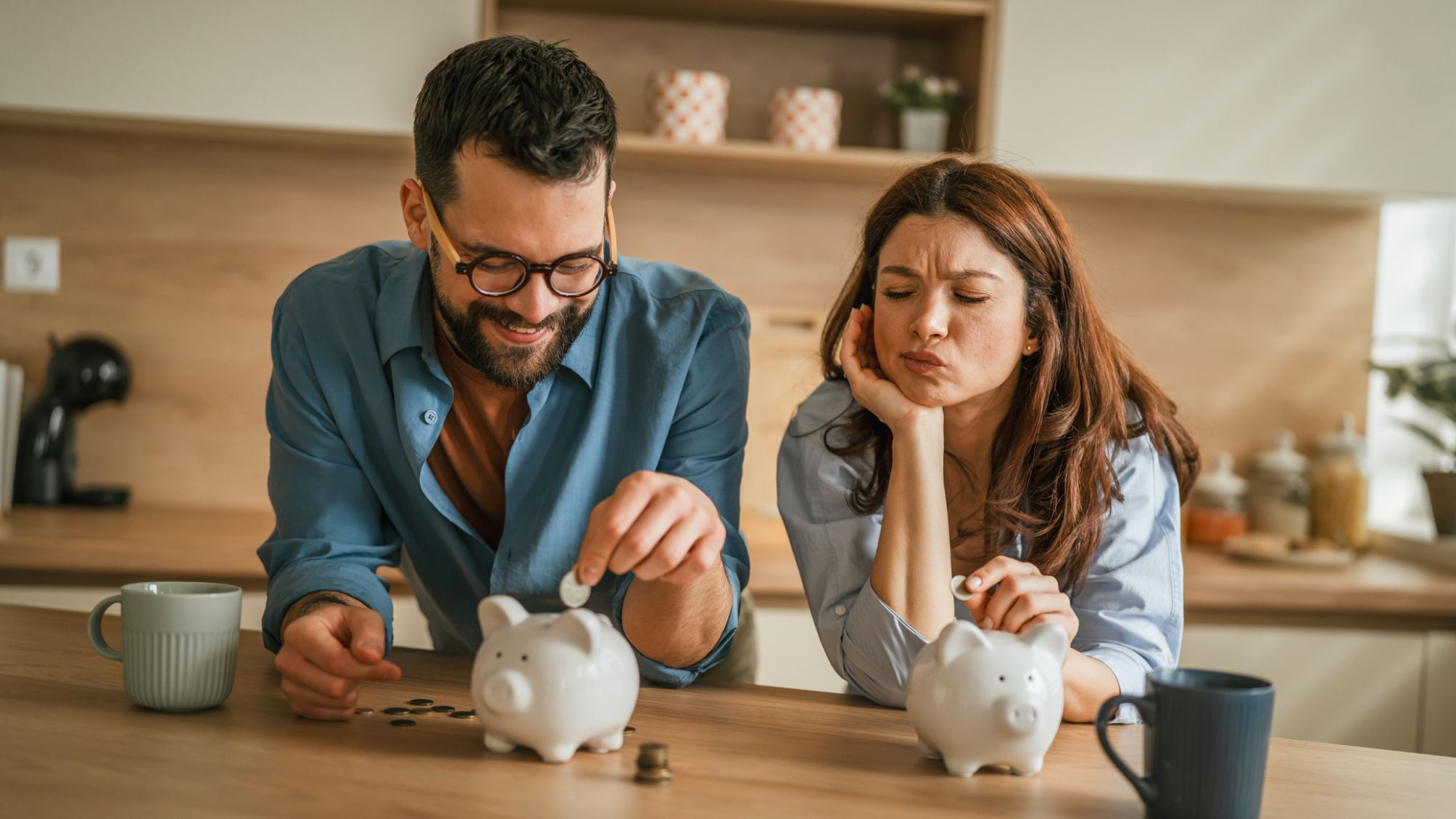 A couple putting money into two piggy banks. 