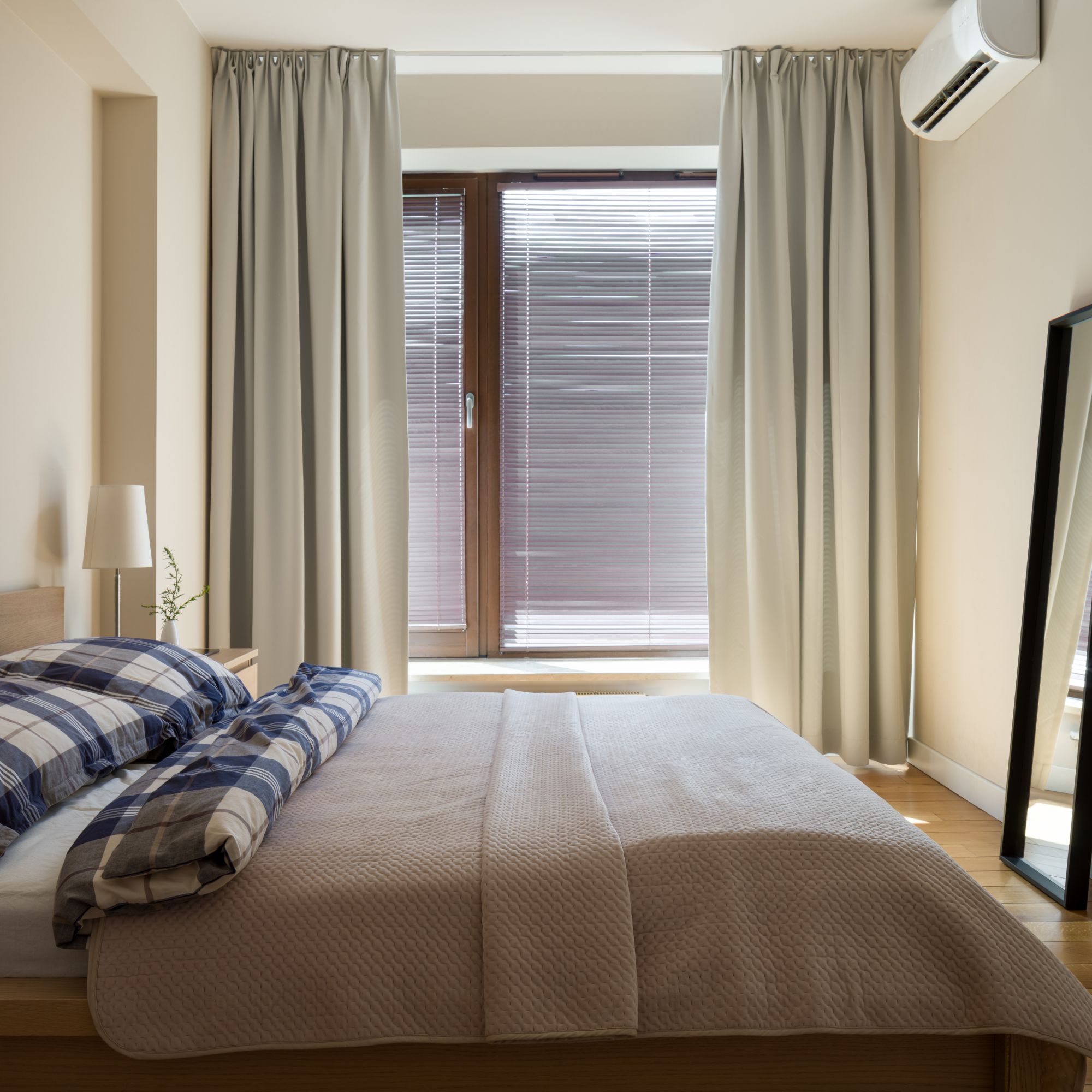 air conditioning unit on wall in a neutral bedroom, installed at the end of the bed