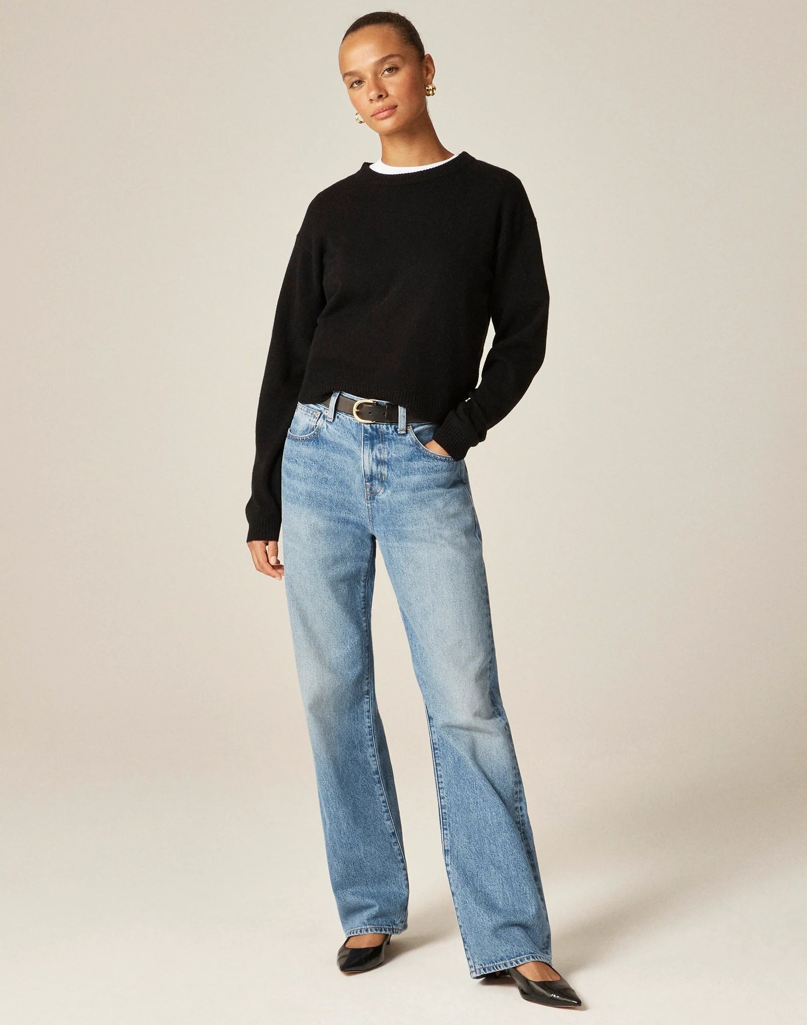 J.Crew fall 2025 outfit idea with a white tee layered under a black crewneck sweater, belt, straight-leg jeans, a back patent shoulder bag, and black patent pumps