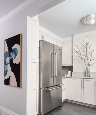 White kitchen scheme with mirrored ceiling light and chrome fridge and accessories