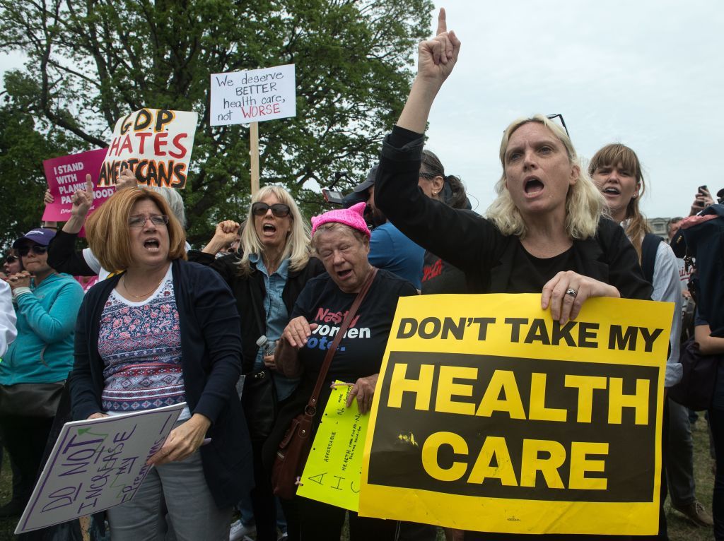 Protesters hold signs and shout at lawmakers walking out of the US Capitol in Washington, DC, on May 4, 2017 