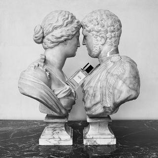 A Celine perfume bottle sits between two roman statues