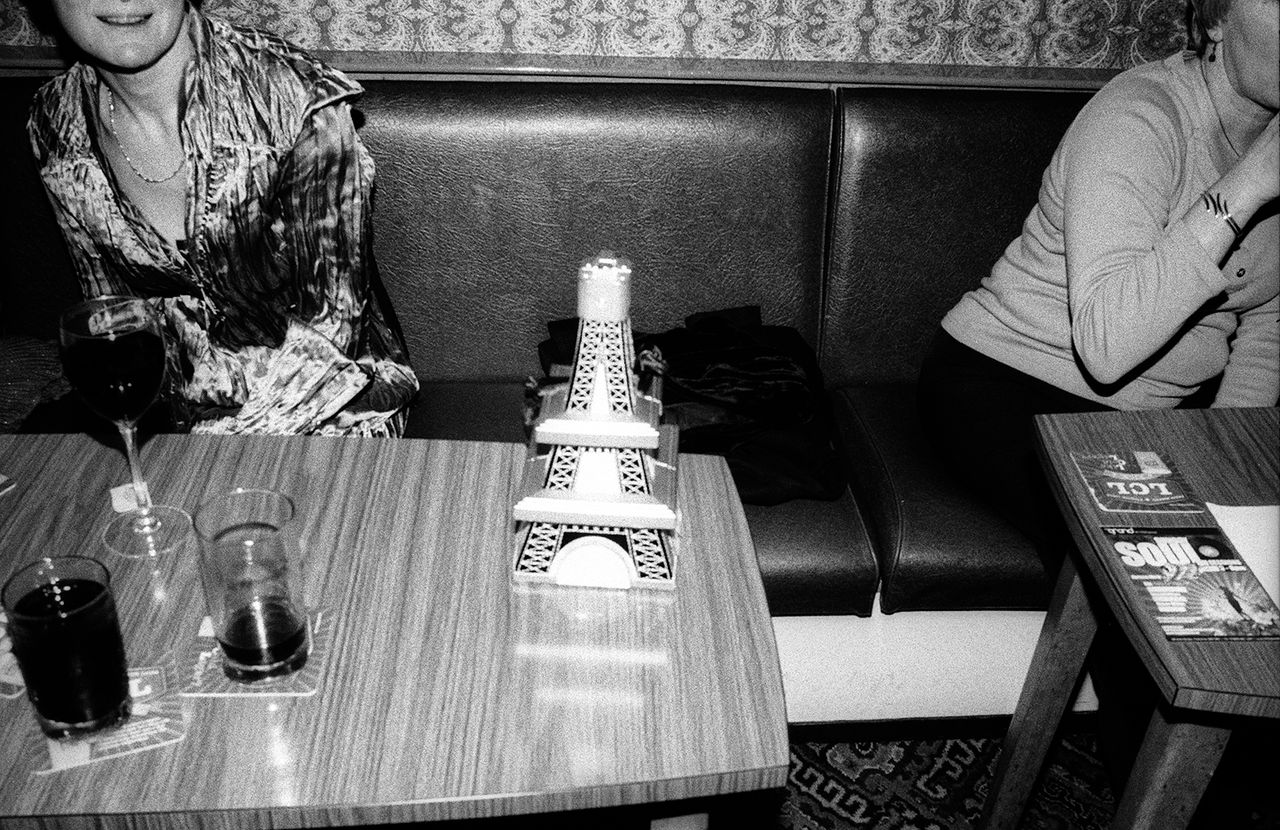 A black &amp; white photo of women having drinks at a bar. They&#039;re sitting down at a booth.