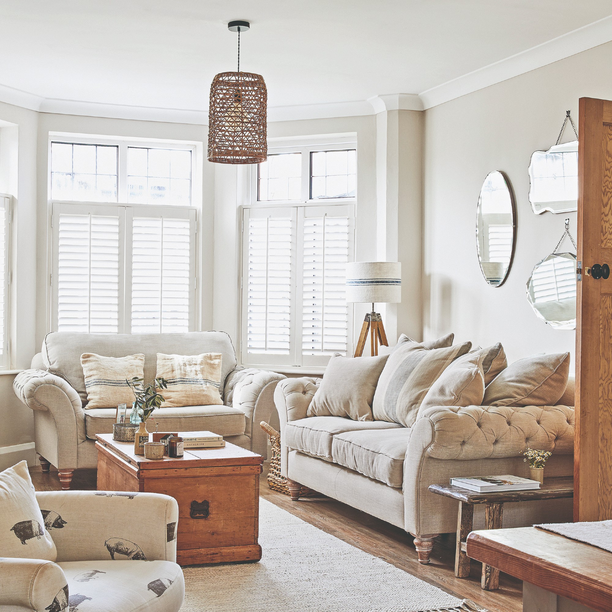 A neutral living room with a matching sofa and loveseat and a wooden chest used instead of a coffee table