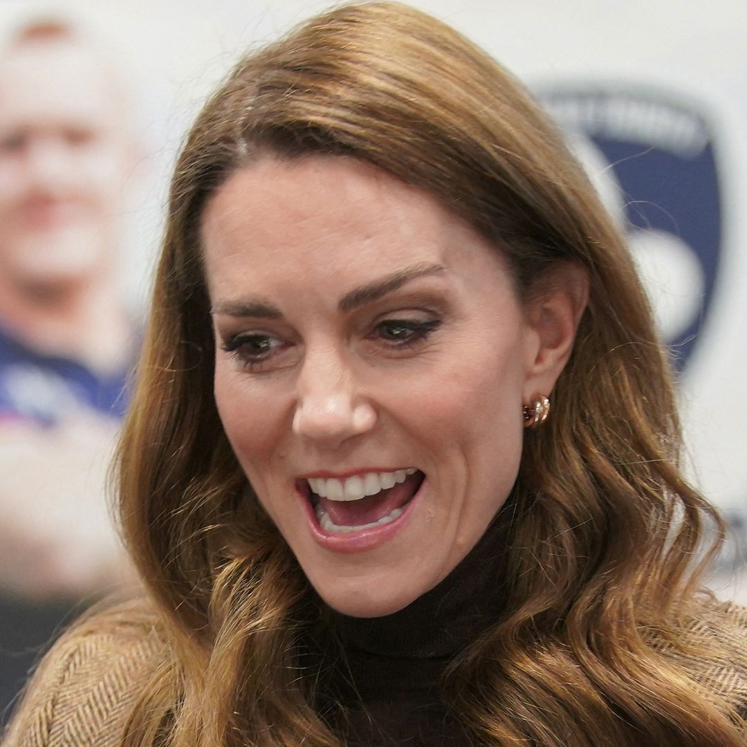 Kate Middleton laughing wearing a brown blazer