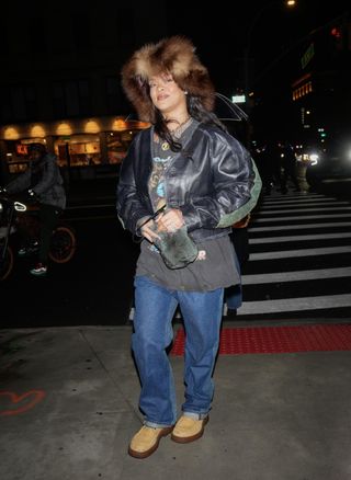 A photo of Rihanna sporting her boyfriend's Bottega Veneta's Haddock boots with a leather jacket, jeans, and a graphic tee on a December Target run in NYC.