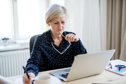 Woman with laptop working in home office.