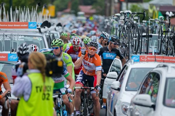 Andre Greipel make shis way through the team cars to the start line