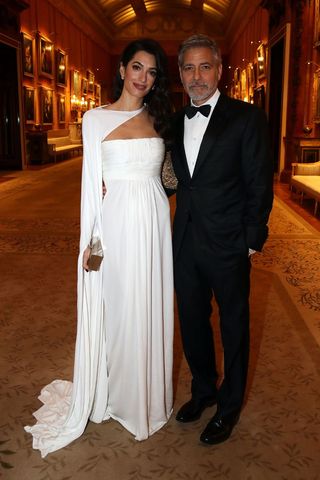 amal clooney wearing a white gown with a cape detail