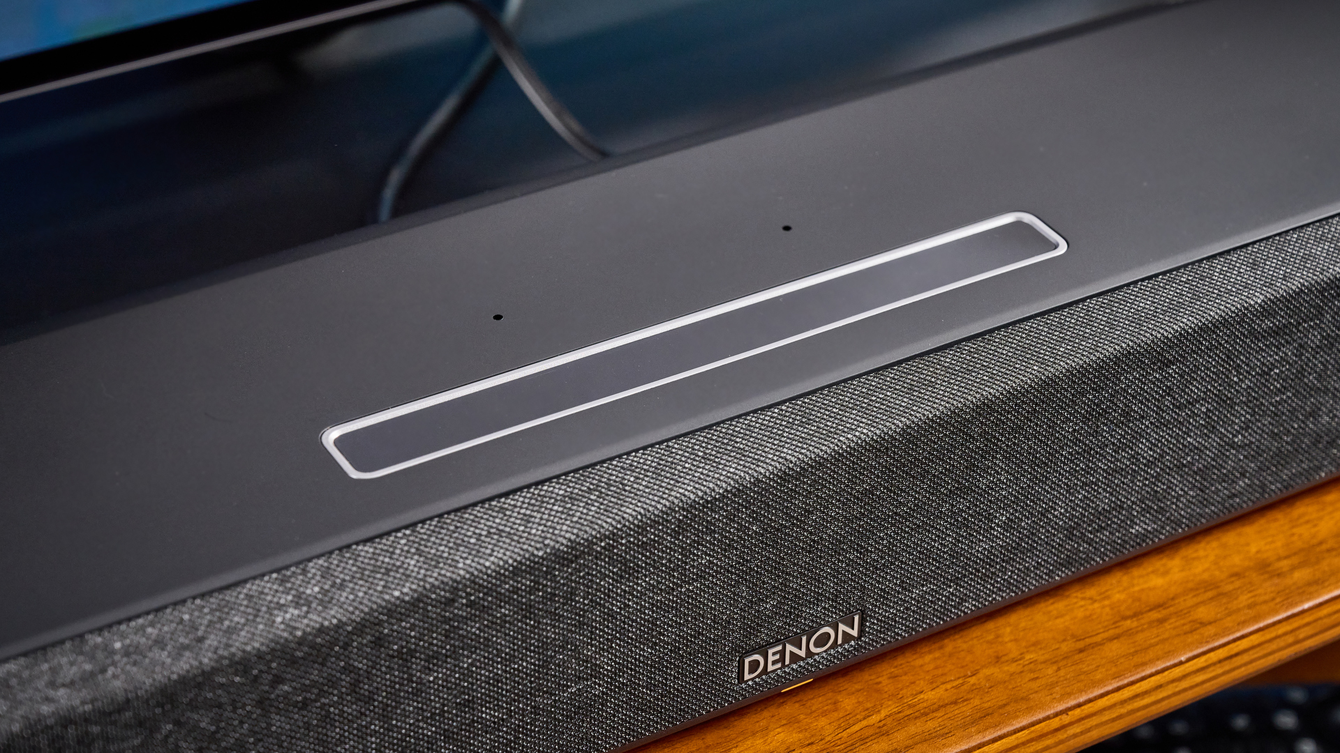 the denon home sound bar 550 with a gray mesh casing and touch controls for bluetooth on the top with a remote and smart home integration