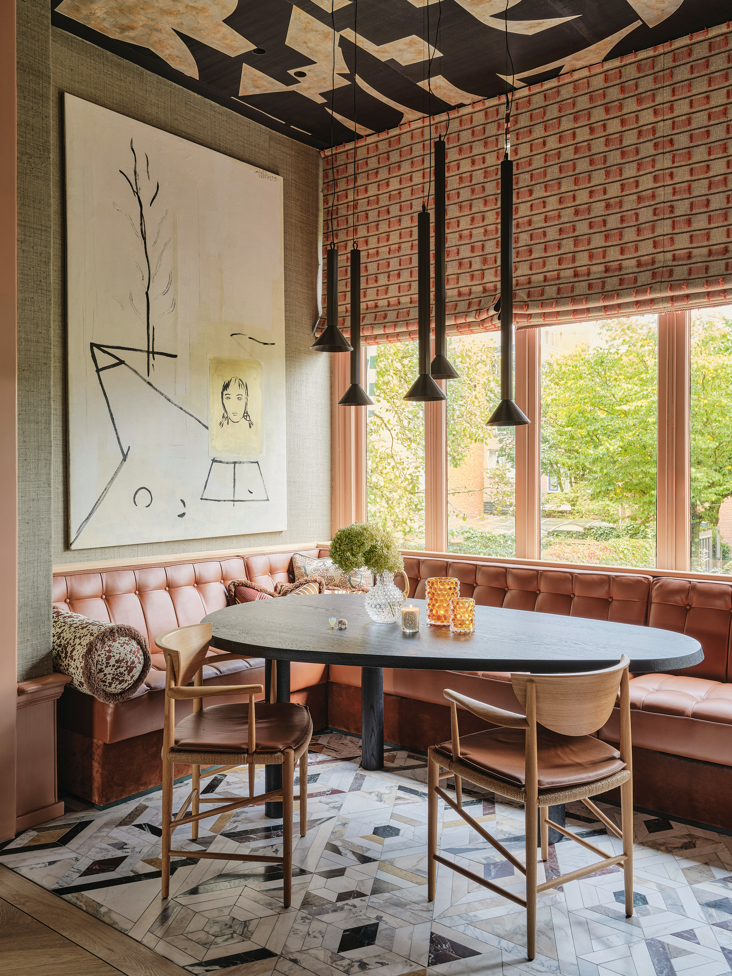 Dining area with pink banquette seating, irregular shaped dining table and light wood chairs