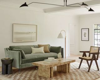 Green velvet couch in modern living room, checkered rug, sculptural metal pendant light