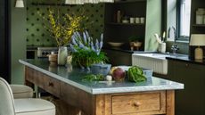 Green kitchen with freestanding wooden and stainless steel breakfast bar island