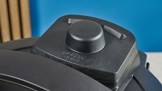 a black instant pot with a dial and touchpad is photographed against a blue background