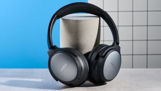 the earfun tune pro headphones, in black, with soft pleather cups, and gray cups, photographed against a blue background
