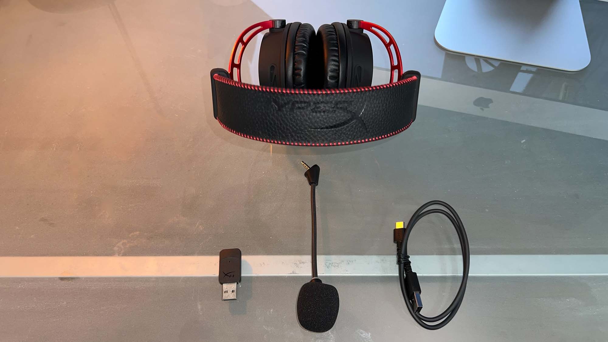 A HyperX Cloud Alpha Wireless gaming headset on a glass desk