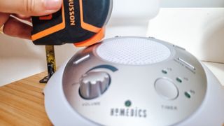 A measuring tape next to a white noise machine