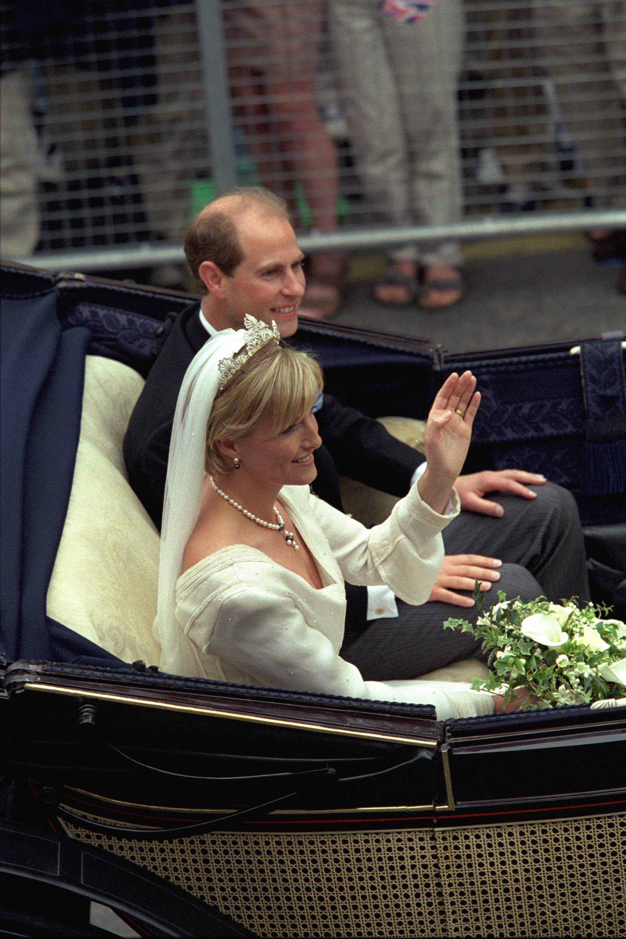 Prince Edward and Duchess Sophie riding in a carriage waving on their wedding day