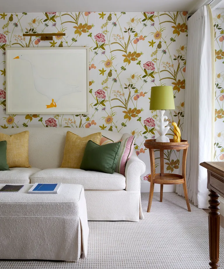 Green floral wallpapered living room with neutral couch and green throw pillows