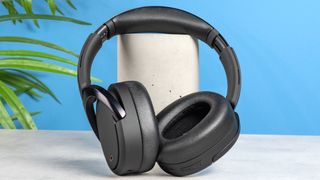 A pair of black Edifier WH950NB over-ear headphones photographed against a blue background