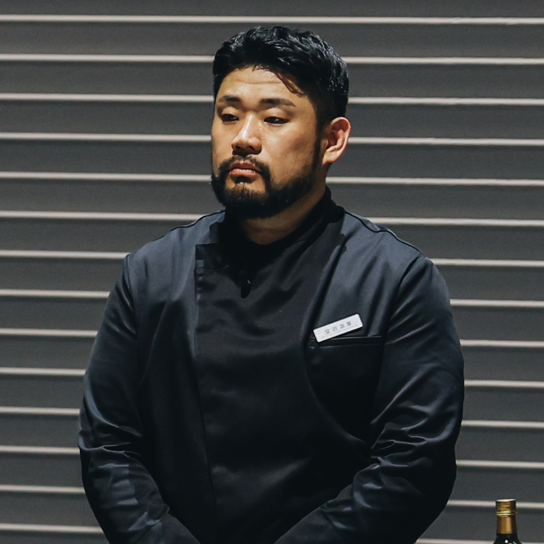 Chef Lee Ha-sung, nicknamed Culinary Monster, stands in front of a wall with horizontal lines, in Netflix's 'Culinary Class Wars.'