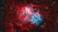 A nebula rages in space with brilliant hues of red and blue.