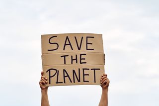 Save the Planet written on a cardboard notice, held by two hands.