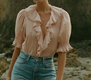 a model wears a light pink ruffled blouse with puff sleevers