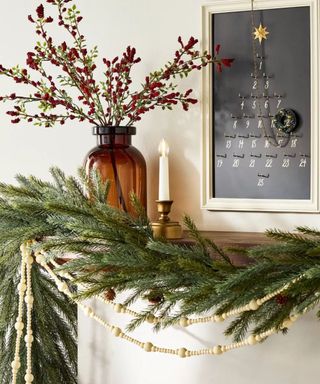 Mantel decorated for Christmas with green garland and wooden beads