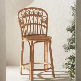 Peacock Rattan Counter Stool against a white wall.