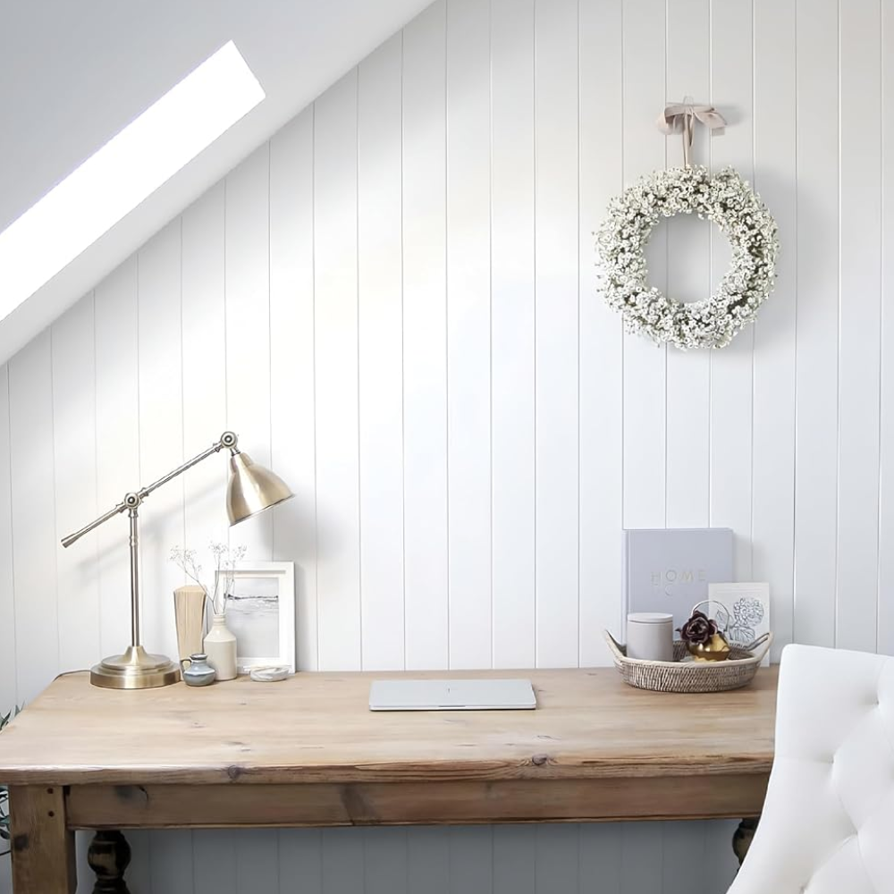 Room with sloped roof, white panelled wall, wooden desk, and white chair just in the shot